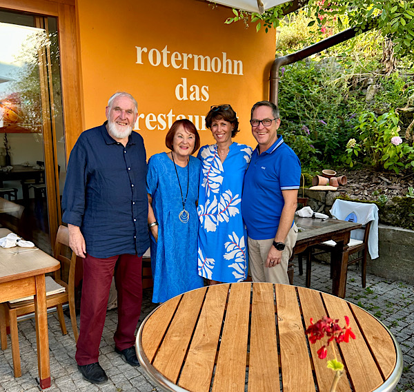 Vier Menschen stehen vor einer orangen Wand auf der "rotermohn" das restaurant" steht