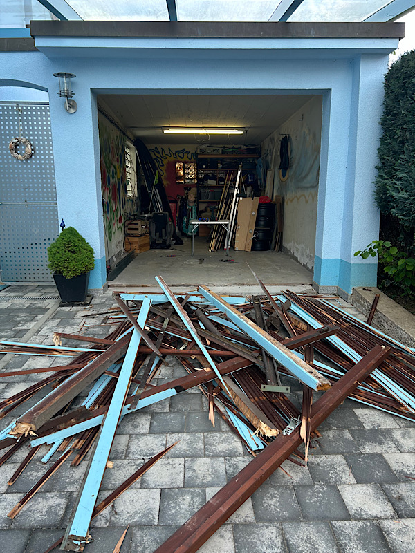 Garage, blau gestrichen, ohne Tor. Das liegt in Trümmern davor