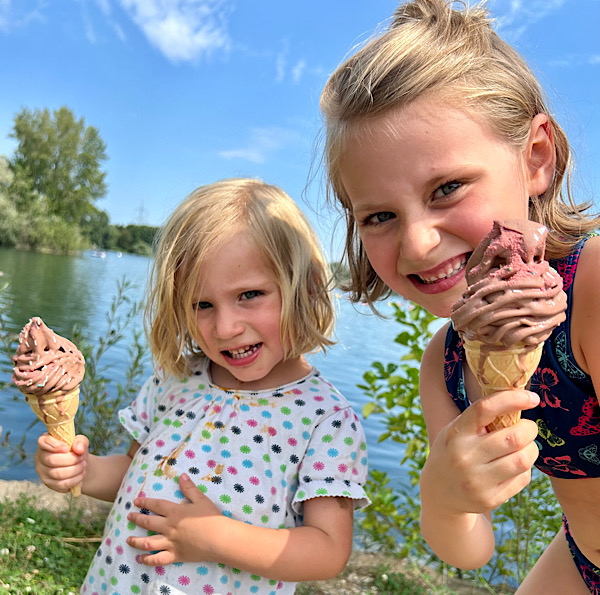 Zwei blonde Kinder am See mit einem Eis in der Hane