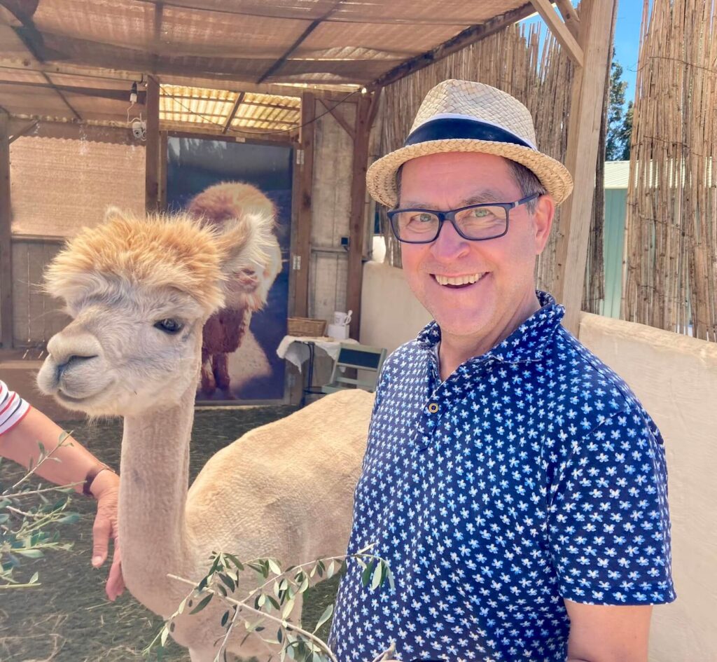 Mann mit Brille und Strohhut (Martin) neben einem Lama